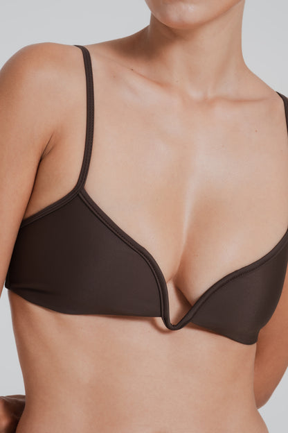 Brown bikini top worn by a person on a plain background
