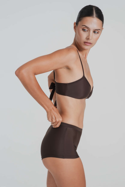 Woman wearing a brown bikini set against a plain background