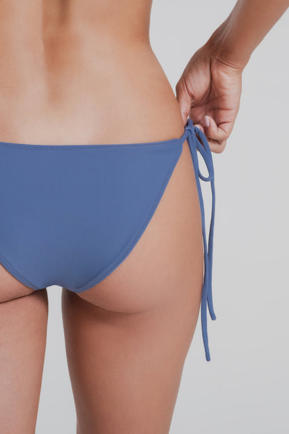 Blue bikini bottom worn by a woman on a plain background
