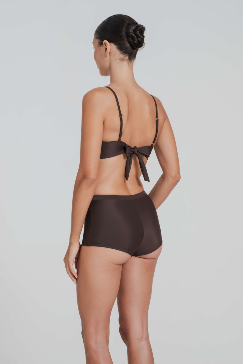 Woman wearing a brown bikini with a plain background